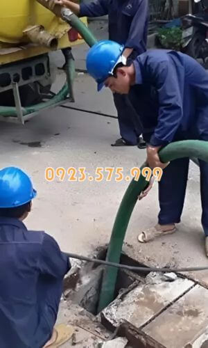 Nhân viên với trang thiết bị bảo hộ đầy đủ đang tiến hành hút bể phốt