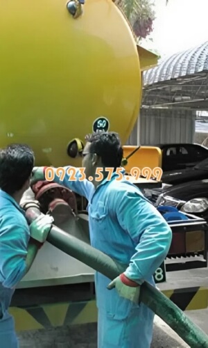 Nhân viên mặc đồ bảo hộ đang chuẩn bị xe hút hầm cầu