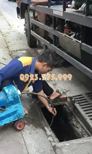 Nhân viên thực hiện thông tắc cống thoát nước ngoài trời